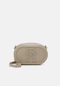 Beige oval leather crossbody bag with embossed logo, zip closure, and detachable strap. Smooth texture and minimalist design.