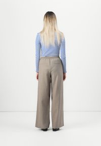 Gestreepte longsleeve top in blauw en wit, gecombineerd met beige wijde broek. De broek heeft een elastische tailleband en achterzakken.