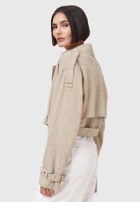 Helle beige cropped Jacke aus Wildleder. Verfügt über einen breiten Kragen, Pattentaschen und gesäumte Ärmel mit silbernen Hardware-Akzenten.