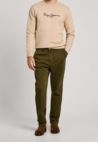 Beige sweatshirt with "Pepe Jeans" logo, olive green chinos, and brown suede boots. Simple, casual design with fitted silhouette.