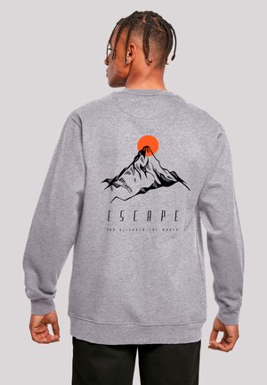 Gray sweatshirt featuring a mountain design with a red sun. Text "ESCAPE" above and "YOU DISCOVER THE WORLD" below the graphic. Long sleeves.