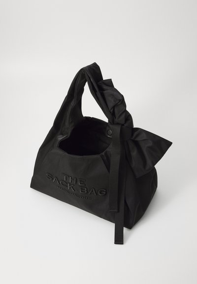 Sac en tissu noir avec une poignée nouée, texte en relief "THE SACK BAG" et "MARC JACOBS". Design légèrement structuré avec une texture douce et mate.