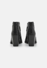 Botines negros de tobillo con textura trenzada, punta afilada y tacón grueso. Cuentan con una cremallera en la parte trasera para su cierre y un acabado suave.