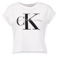 Bílý bavlněný crop top se potiskem loga "Calvin Klein Jeans" v černé barvě. Krátké rukávy a volný střih. Hladká textura.