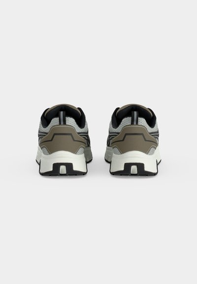 Paire de chaussures de sport grises et noires avec semelles blanches montrées de dos sur un fond clair uni.