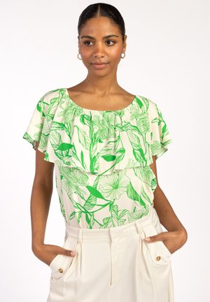 Korte mouw blouse in crème met groen bloemenpatroon, met een ruches halslijn en een ontspannen pasvorm. Gecombineerd met crème broek met zijzakken.