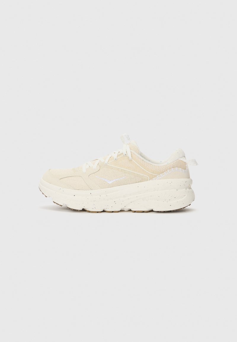 Beige athletic shoe with a textured mesh upper and a white rubber sole, featuring speckled details and traditional lacing system.