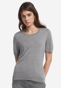 Grå kortærmet sweater med rund halsudskæring og ribbede manchetter. Blød tekstur, afslappet pasform med diskrete syninger ved kanten.