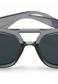 Gros plan de lunettes de soleil rectangulaires noires avec des montures épaisses et des verres teintés foncés, montrant le design distinctif ajouré du pont.