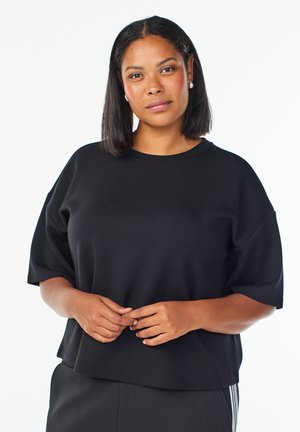 Sort, oversized kortærmet top lavet af blødt stof. Har en rund halsudskæring og en afslappet pasform, der er velegnet til uformelt tøj.