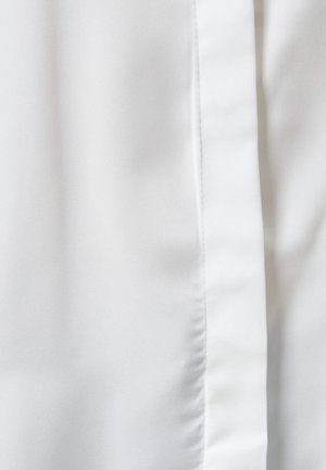 Weißer Stoff mit einer glatten, seidigen Textur, der einen subtilen Glanz aufweist und über eine vertikale Nahtdetail am rechten Rand verfügt.