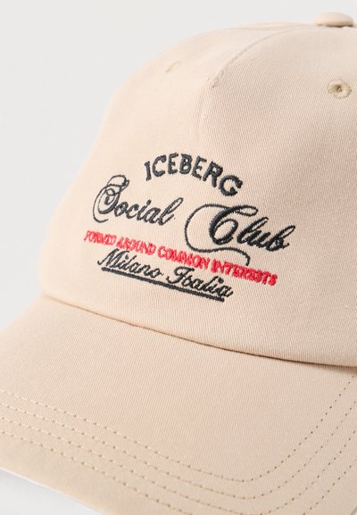 Μπεζ καπέλο μπέιζμπολ με κεντημένο κείμενο "ICEBERG Social Club" σε μαύρο και "FOUNDED AROUND COMMON INTERESTS Milano Italia" σε κόκκινο και μαύρο.