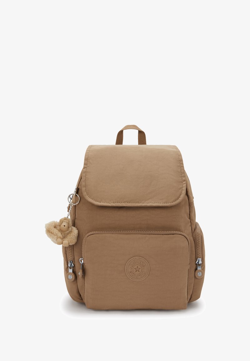 Hnědý batoh s překlapávacím víkem, kapsou na zip a připevněným chlupatým klíčenkou v podobě opice. Na přední straně se nachází kulatý znak. Texturovaná látka.
