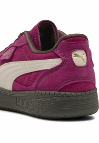 Sneaker Puma con tomaia in suede rosa, striscia in pelle bianca e suola scura con motivi a stella. Logo dorato sul tallone.
