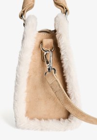 Tanhandske i ruskind set fra siden med hvid imiteret pelskant og aftagelig strop fastgjort til sølvfarvet metalkrog.