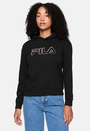 Felpa nera con tasca a marsupio e polsini a coste, con un logo FILA in gradiente viola e bianco. Indossata con jeans azzurri chiari.