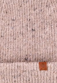 Różowa dziana czapka z splotem, z podwiniętym mankietem i brązową skórzaną metką z symbolem krzyża.