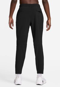 Czarne spodnie sportowe z elastycznym paskiem, zwężanymi nogawkami i zamykaną na zamek kieszenią po prawej stronie. Wykonane z lekkiego, gładkiego materiału.