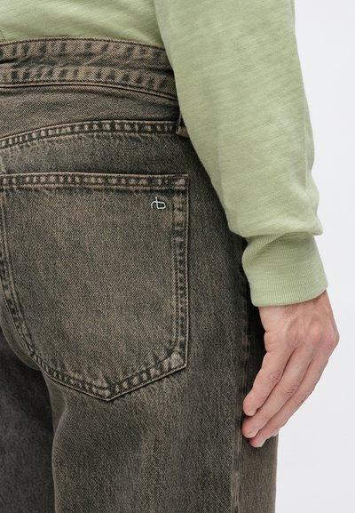 Dark grey denim jeans with a textured finish, featuring a back pocket with a subtle white logo, paired with a light green long-sleeve shirt.