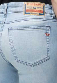 Jean Diesel bleu clair montrant la poche arrière et l'étiquette de marque en cuir avec un texte sur la qualité et la garantie depuis 1978.
