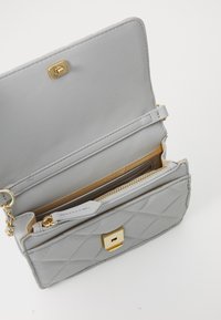Portafoglio grigio trapuntato in materiale sintetico con hardware dorato. Caratterizzato da un compartimento con zip e multiple fessure per carte, con chiusura a scatto.