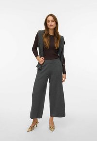 Pantalon gris à jambes larges en tricot texturé, associé à un haut moulant marron foncé et orné de talons pointus à motifs.