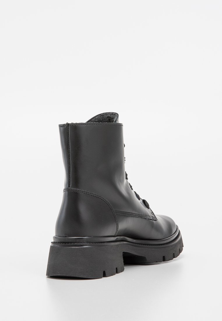 Schwarzes Leder-Ankle-Boot mit einer groben Sohle, Schnürdesign und glatter Oberfläche. Verfügt über ein strukturiertes Stofffutter, das oben sichtbar ist.