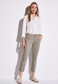 Lätt, vit skjorta med lång ärm. Oljefärgad, kort byxor med framfickor. Beige snörskor med en texturerad yta.
