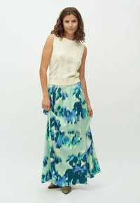 Top senza maniche in maglia color crema con una texture floreale abbinato a una maxi gonna fluida con un motivo astratto verde e blu.