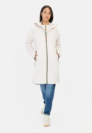 Lichtgewicht, lange beige jas met een capuchon, voorruit en houten accent. Heeft zijzakken en is gestyled met blauwe jeans.