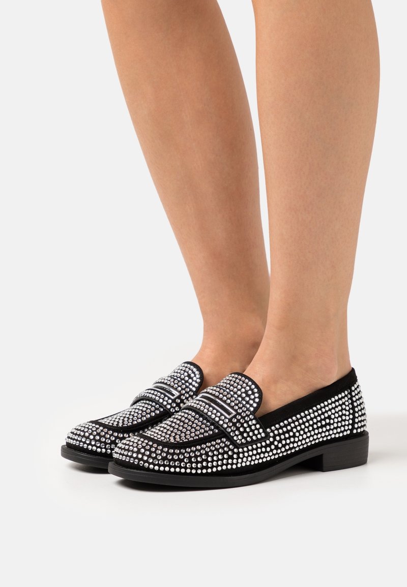 Mocassins noirs ornés de strass en argent, avec un dessus lisse, un talon bas et un design classique avec deux bandes décoratives.