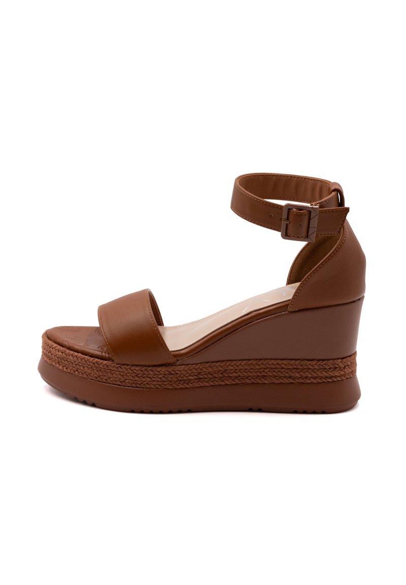 Bruine leren wedge sandaal met een enkelband en een geëtaleerd gevlochten plateau. Beschikt over een glad bovenwerk en een gevoerde voetbed.