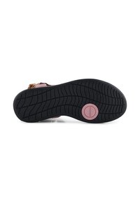 Svart gummisula med ett mönstrat mönster, som har en rosa cirkulär logotyp. Skornas ovandel är en mix av ljusa färger och texturer.