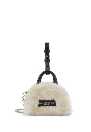 Petit sac à main beige en fourrure avec poignée et bandoulière en cuir noir, chaîne dorée et patch logo "Lancaster Paris" à l’avant.