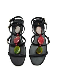 Sandalias planas negras con múltiples tiras finas. Presentan grandes piedras decorativas coloridas en rojo, verde y marrón en la tira central.