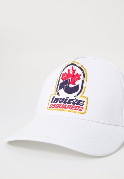 Casquette de baseball blanche avec un pic arrondi. Présente un logo brodé proéminent avec une feuille d'érable rouge et le texte "invicta DSQUARED2." Texture lisse.