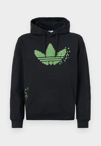 Svart hoodie i bomull, med en stor grön pixelartad trefoil-logga på fram- och sidan. Inkluderar en känguruficka och ribbade muddar.