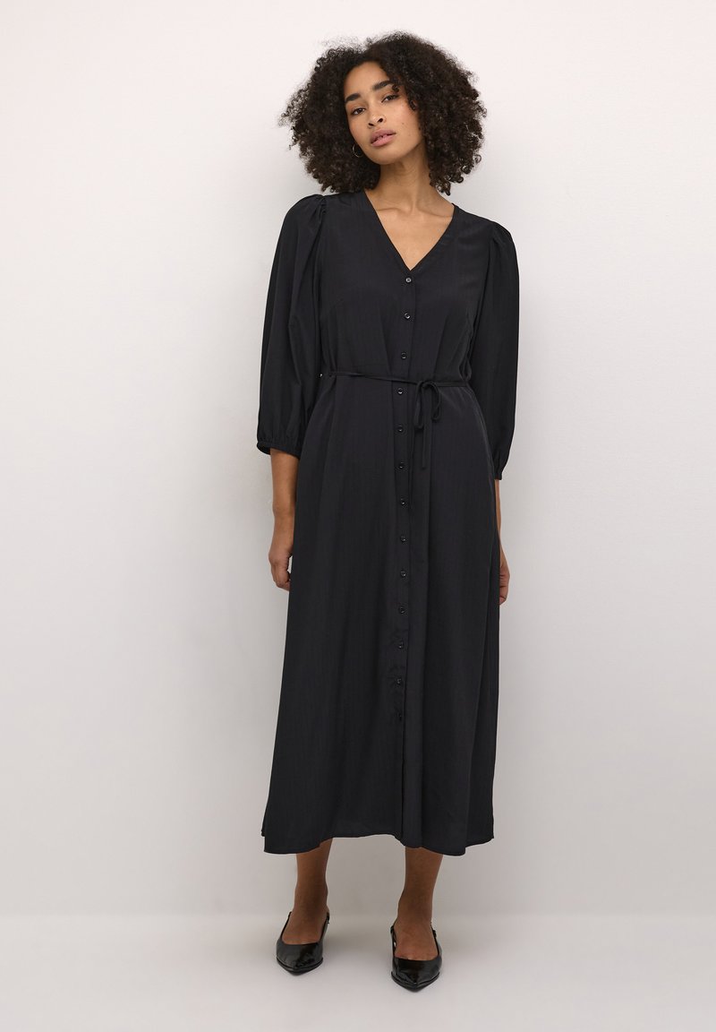 Robe noire midi avec un décolleté en V, des manches bouffantes trois-quarts, un devant à boutons et une taille nouée. Tissu lisse avec une texture subtile.