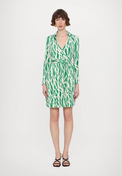 Robe enveloppante verte et crème à manches longues, avec un motif vertical de lignes abstraites. Décolleté en V et détail de lien à la taille.