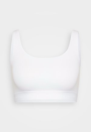 White seamless sports bra with wide straps and elastic band featuring subtle "organic basics" text, displayed on plain light background.