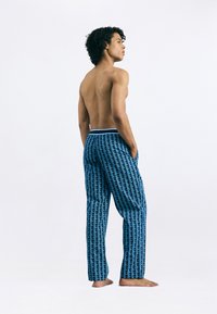 Calças de pijama com padrão azul e design geométrico, cintura elástica com um tom de azul claro, e dois bolsos laterais.