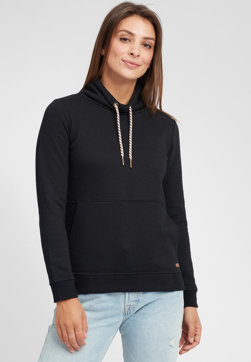 Schwarzer Hoodie mit hohem Kragen, ausgestattet mit verstellbaren Zugbändern mit metallischen Enden. Hergestellt aus weichem Material, mit einer Vordertasche und gerippten Bündchen.