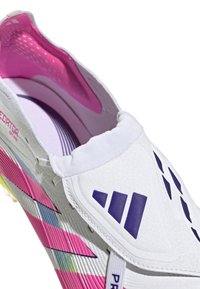 Chaussure de football blanche avec un bout arrondi, une tige texturée, des accents violets, une semelle intercalaire rayée arc-en-ciel et un col rembourré semblable à une chaussette.