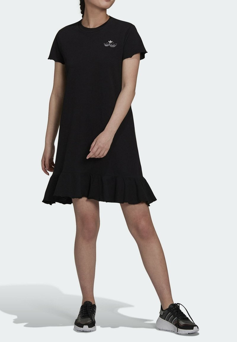 Černé bavlněné šaty s krátkými rukávy, kulatým výstřihem a volánkovým lemem. Obsahují malé logo na hrudi a mají volný střih.