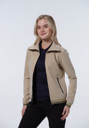Beige zip-up jacket with a high collar, black accents, and gold-striped cuffs. Smooth fabric texture with side zip pockets.