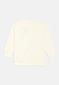 Kremo spalvos džemperis su ilgomis rankovėmis, ribėtomis rankogaliais ir apvalia iškirpte. Minkšta medžiaga su lygiu paviršiumi. Be matomų grafinių elementų.