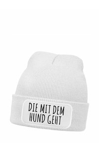 White knitted beanie hat featuring a folded cuff and a rectangular patch with the text "DIE MIT DEM HUND GEHT" in black lettering.
