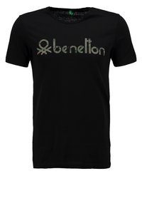 Černé bavlněné tričko s výrazným kovovým logem "benetton" na hrudi. Krátké rukávy a kulatý výstřih.