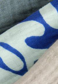Trois échantillons de tissu : lin texturé gris, bleu clair avec un motif abstrait bleu foncé, et textile tissé beige.