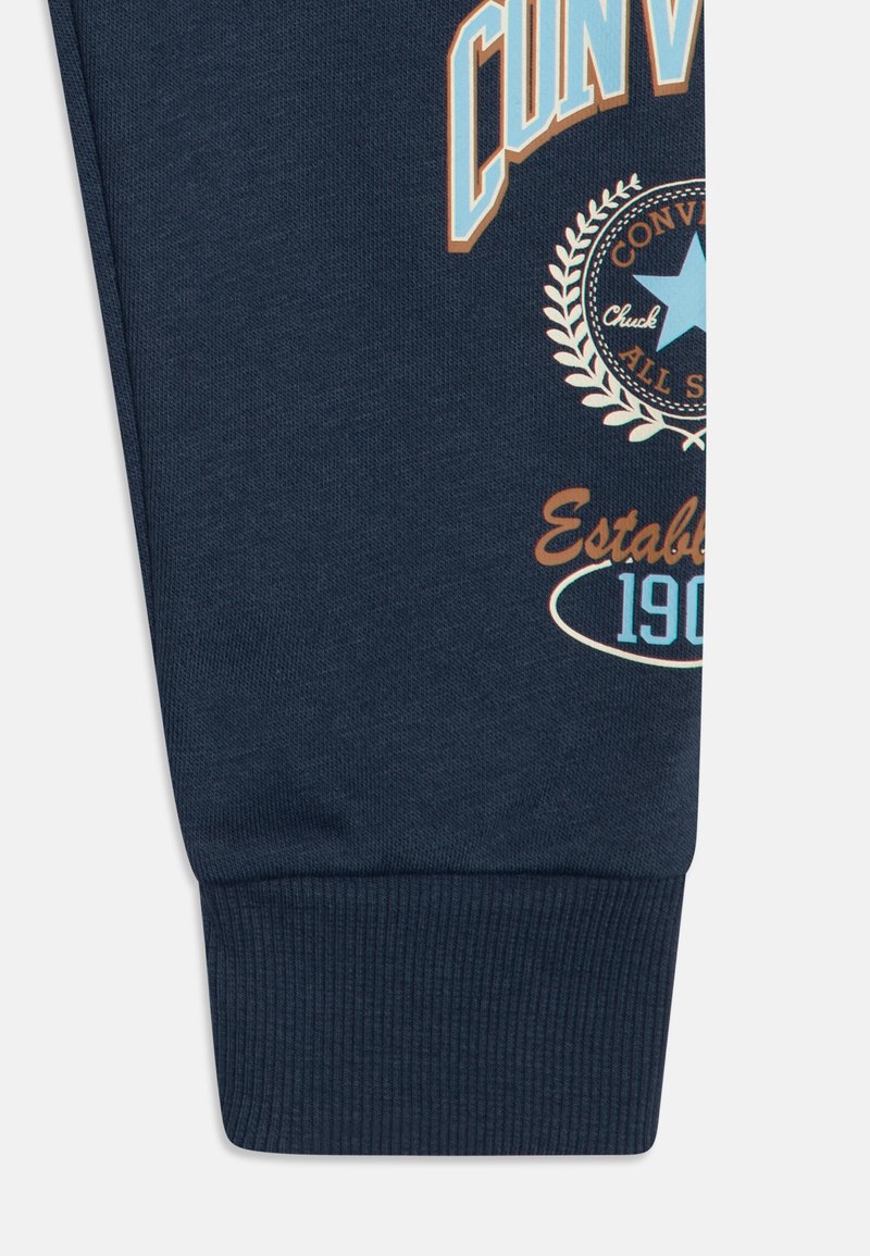 Cuff di felpa blu navy con testo stampato ed elementi decorativi in blu chiaro e marrone, caratterizzato da una texture a costine.